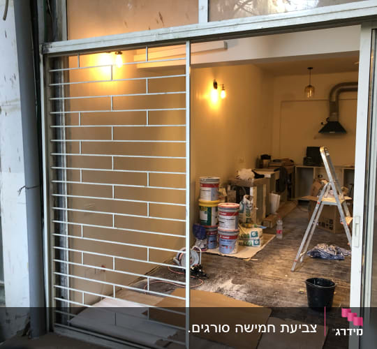 פחיות צבע וסולם בחדר במהלך צביעה
